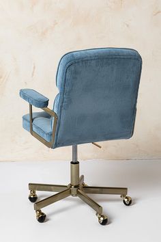 a blue office chair sitting on top of a white floor next to a beige wall