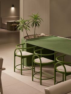 a green table with four stools and a potted plant on it in a room