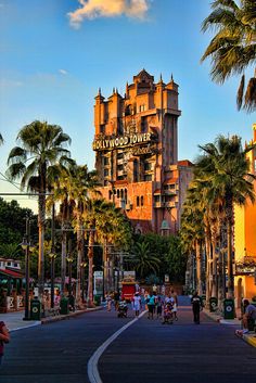 the hollywood tower hotel is surrounded by palm trees and people walking down the street in front