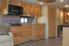 the interior of an rv with wood cabinets and tile flooring, including a couch