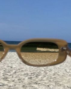 a pair of glasses sitting on top of a sandy beach