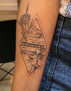 a woman's arm with a tattoo on it that has books and flowers in the middle