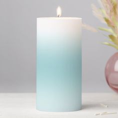 a white and blue candle sitting on top of a table next to a pink vase