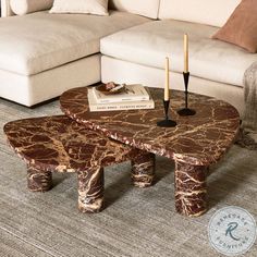 a marbled coffee table with two candles on it in front of a white couch