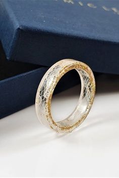 a close up of a ring on a table near a blue box with gold foil