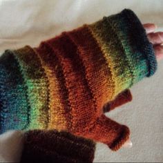 a hand is holding a multicolored knitted mitt