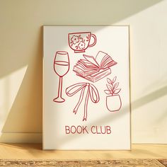 a book club poster on the wall next to a glass of wine and an open book