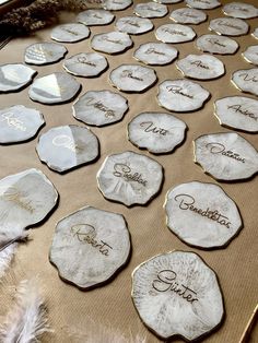 some white and gold plates with names on them sitting on a brown tablecloth covered surface