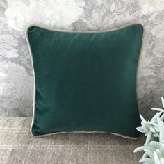 a green pillow sitting on top of a couch next to a white succulent plant