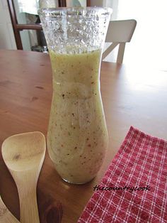 a wooden table topped with a glass vase filled with liquid next to a wooden spoon