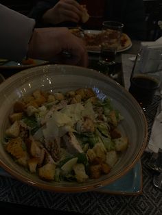 a bowl filled with food sitting on top of a table next to plates and glasses