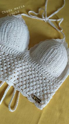 a white crocheted brach laying on top of a yellow cloth covered bed