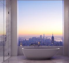 a bath tub sitting in the middle of a bathroom next to a large window overlooking a city