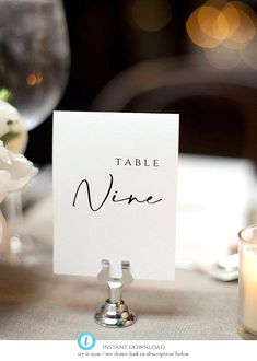 a place card sitting on top of a table next to a vase with white flowers