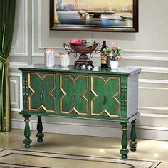 a green and gold sideboard in a living room with a painting on the wall