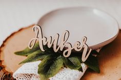 the word august is spelled with wooden letters on a piece of wood next to a white plate