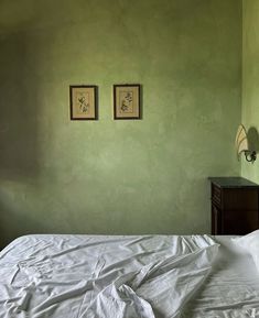 a bed with white sheets and two pictures on the wall