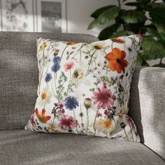 a flowered pillow sitting on top of a gray couch