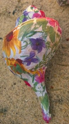 an odd shaped object with flowers painted on it's sides sitting in the sand