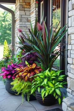 two large potted plants sitting on top of a stone walkway next to a brick building