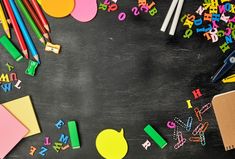 colorful school supplies laid out on top of a blackboard with the letters and numbers