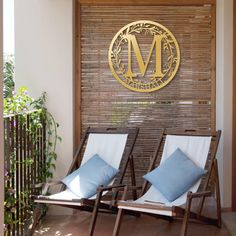 two lounge chairs with blue pillows in front of a wooden sign that says m on it