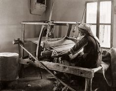 an old black and white photo of a woman working on a loom in a room