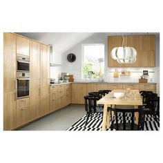 a modern kitchen with black and white checkered rugs on the floor, wooden cabinets and an oval pendant light fixture