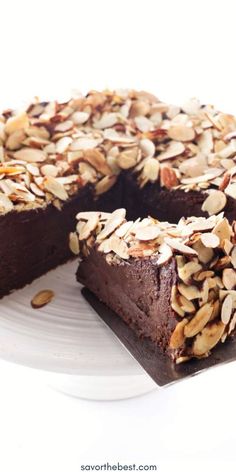 there is a chocolate cake with nuts on the top and one slice missing from it