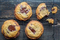 four chocolate chip cookies on a cooling rack with one broken in half and the other partially eaten