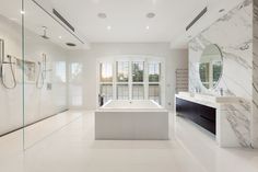 a large white bathroom with two sinks and a bathtub in the middle of it