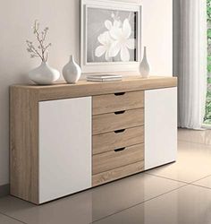 a white and wood dresser with three vases on it's sideboard next to a window