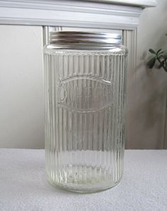 a clear glass jar sitting on top of a table next to a window sill