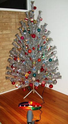 a silver christmas tree with many ornaments on it