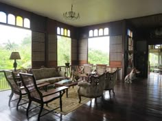 a living room filled with lots of furniture next to large windows on top of a hard wood floor