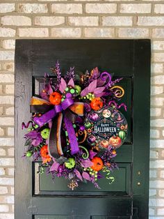 a halloween wreath on the front door of a house that is decorated with purple, orange and green decorations