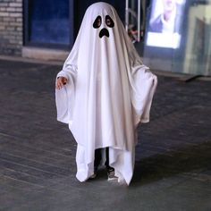 a little boy dressed in a ghost costume