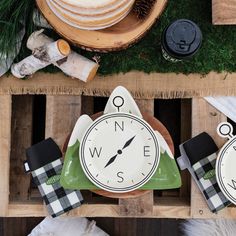 three clocks sitting on top of a wooden crate next to pine cones and other items