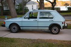 an old blue station wagon parked on the sidewalk