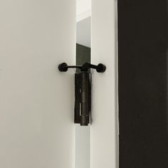 an open door with a black handle on the front and side of it, in a white room