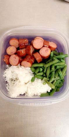 a plastic container filled with rice and sausage next to green beans on top of it