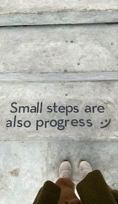 someone standing on the ground with their feet up in front of a sign that says small steps are also progress