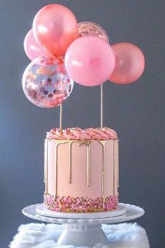 a cake with pink frosting and balloons on top