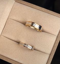 two gold wedding rings sitting in a box