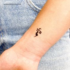 a person with a small tattoo on their left wrist and an electrical symbol in the middle