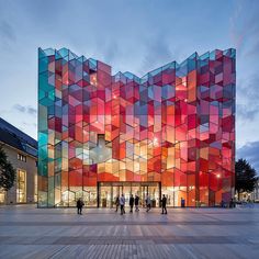 people are walking around in front of a multicolored building with many squares on it