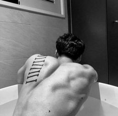 a man is sitting in the bathtub with his back turned