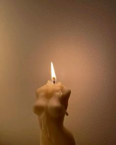 a candle that is sitting on a table next to a wall with a light in it