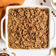 a casserole dish filled with granola and pecans on a white table