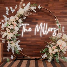 the miller's sign with flowers and greenery on it in front of a wooden wall